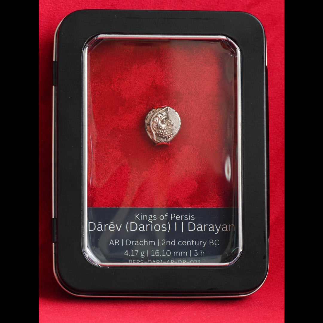 A small ancient silver coin of Dārev (Darius) from the Persian Aryan dynasty, displayed inside a black metal case with a red velvet interior and a clear plastic cover. The case features a black label at the bottom with white text detailing the coin's specifications.